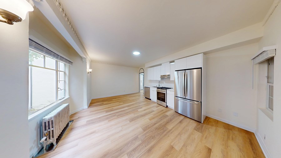 A kitchen with a refrigerator, oven, and sink is visible.